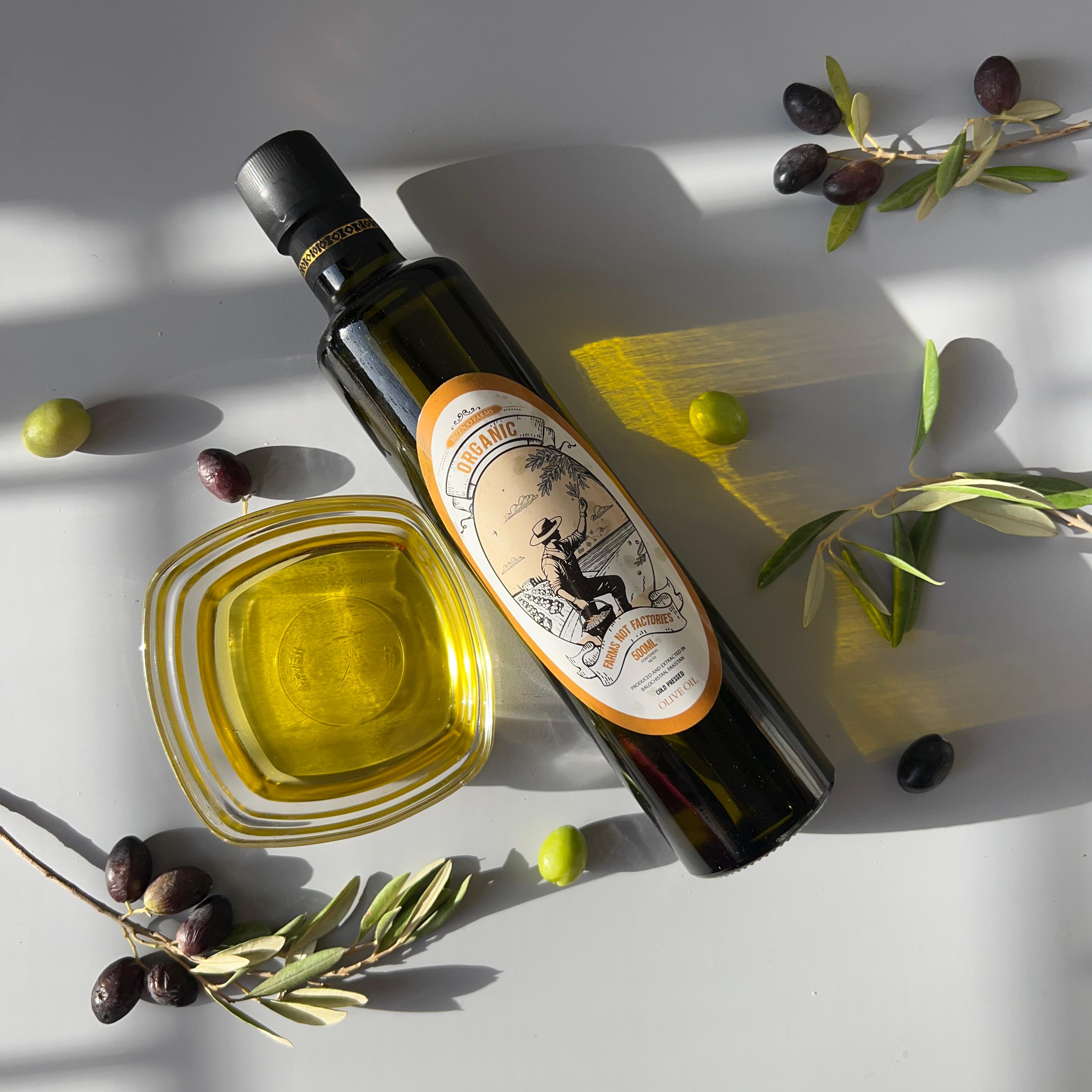 Bottle of olive oil with a label, surrounded by olives on a light background